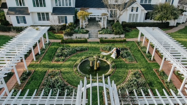 An aerial view of couple Katie and Billy strolling the Fearrington Gardens during their wedding day