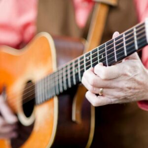 picture of a man's fingers playing an acoustic guitar
